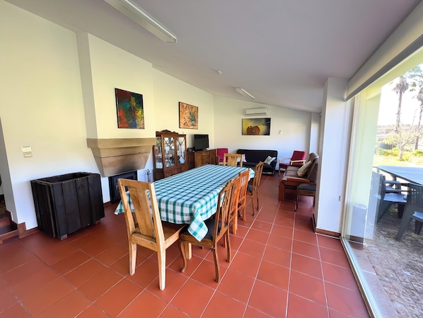 Un coin repas avec une nappe à carreaux, des chaises en bois, un canapé et une cheminée.