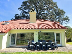 A house with a red-tiled roof, a chimney, and a covered patio with outdoor furniture.