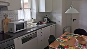 Une cuisine moderne avec des meubles blancs, un four à micro-ondes, un évier et un coin repas comprenant une table et des chaises.