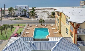 Relax by the rectangular pool surrounded by lounge chairs, overlooking the adjacent beach.