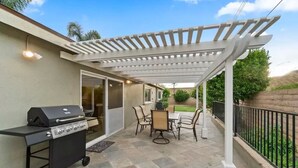 An outdoor patio with a grill, a covered seating area, and a view of the backyard. - *Reduced Pricing* Spacious Disney Vacation w/ Game Room (Orange)