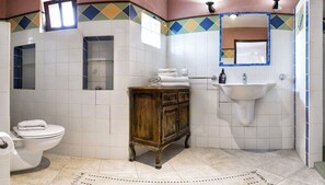 A bathroom with a toilet, a wooden cabinet, a sink, and a mirror. - Sato Triopia Butik Otel (Datça)