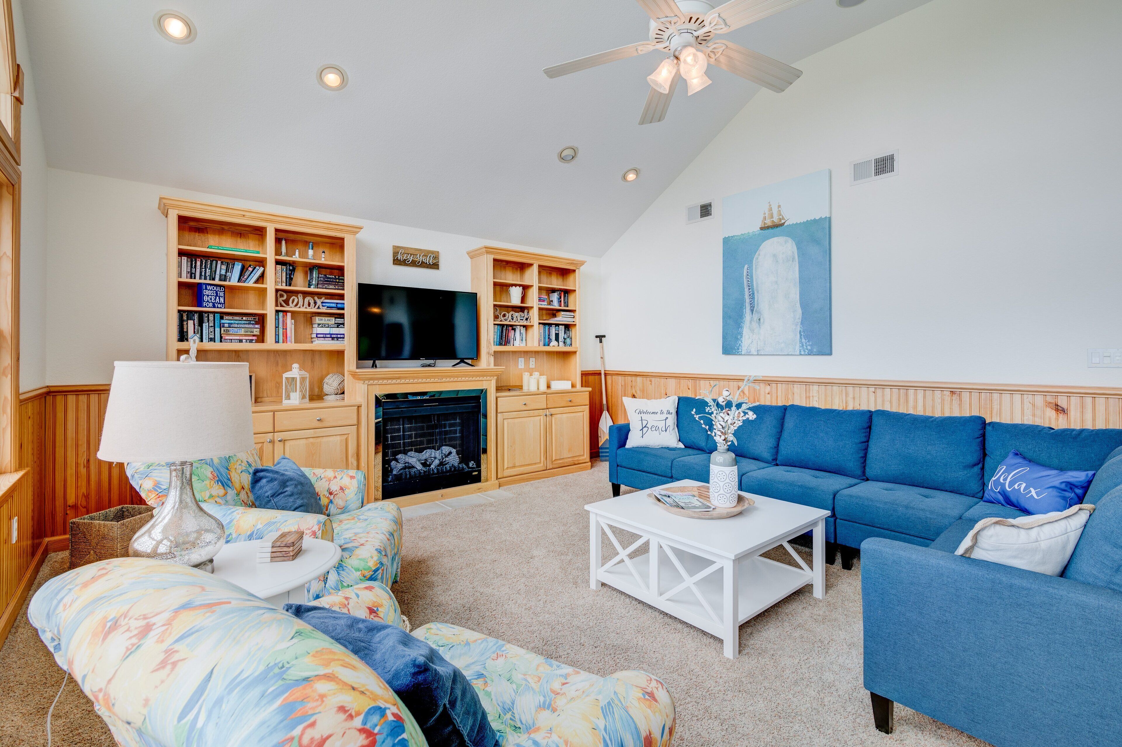 A living room with a television, bookshelves, a blue sofa, and a fireplace.
