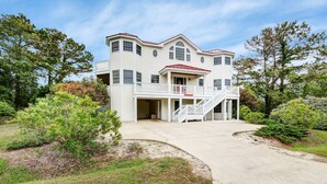 A large, two-story house with a covered front porch and a staircase leading to the entrance. - 1069 - Seadation - Lakeview Corolla Escape w/ Pool & Hot Tub (Corolla)