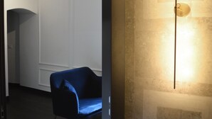 A modern interior with a blue chair, a wall-mounted light fixture, and a wooden floor.