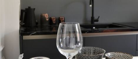 A modern kitchen with a dark countertop, a sink, and a glass cabinet above the stove.