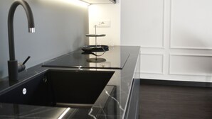 A modern kitchen with a black countertop, stainless steel sink, and a built-in range hood.
