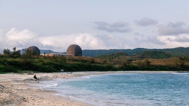 A beach with two large dome structures, a sandy shore, and a hilly landscape in the background. - Sunmiao Inn (Hengchun)