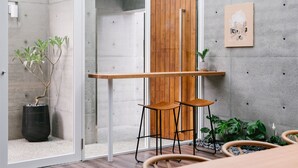 A modern interior with a concrete wall, a wooden door, a glass partition, and a small table with two chairs. - Sunmiao Inn (Hengchun)