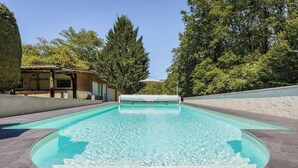 Une piscine rectangulaire avec un élément décoratif aquatique à l’eau claire au centre, entourée d’une terrasse dallée.