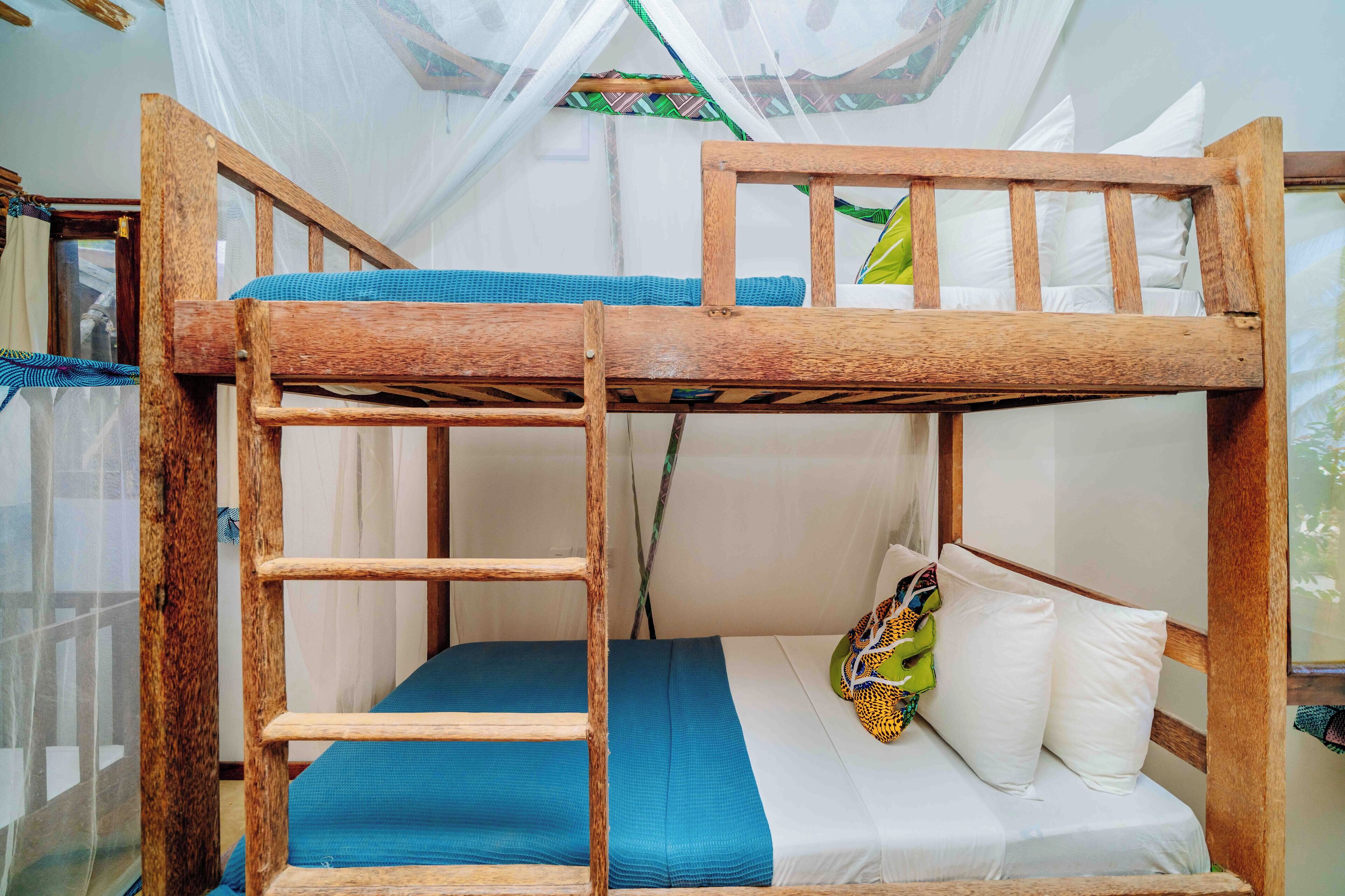 A bunk bed with a wooden frame, a blue mattress, and white pillows.
