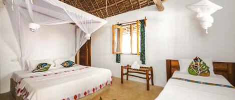 A room with two beds, a wooden bench, a window with curtains, and a thatched roof.