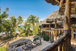 A beachside resort with thatched-roof structures, palm trees, and a sandy beach. - Shanuo Beach Bungalows (Michamvi)