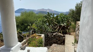 A stone pathway leading to a white-painted structure with a view of a mountain and a body of water. - Traditional Eolian House "Luna"- Unique experience (Lipari)