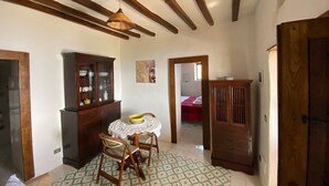 A room with a wooden ceiling, a dining table with chairs, a cabinet, and a bed in the background. - Traditional Eolian House "Luna"- Unique experience (Lipari)