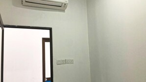 Una habitación con pared blanca, una puerta con marco azul y un equipo de aire acondicionado montado encima.