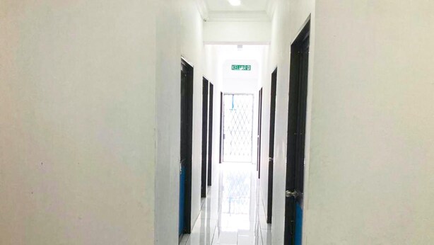 Un pasillo con puertas a ambos lados, suelo de baldosas y un letrero que indica una salida.