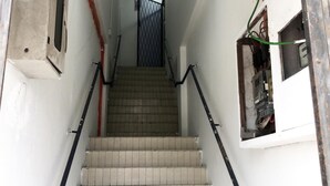 Una escalera con escalones de cerámica, barandilla de metal y una puerta al final.