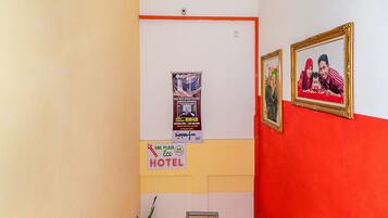A hotel corridor with a red and white wall, a poster advertising the hotel, and a framed photo on the wall.