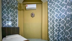 A hotel room with a bed, an air conditioning unit, patterned curtains, and a decorative wall piece. - SPOT ON 90042 One Plaza Eco Hotel (Keningau)
