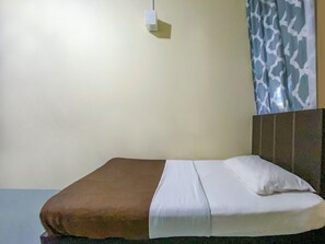 A neatly made bed with a brown blanket and white sheets, a headboard with a textured pattern, and a wall-mounted light fixture. - SPOT ON 90042 One Plaza Eco Hotel (Keningau)