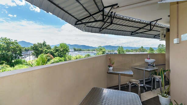 A balcony with a metal table, a small stool, and a potted plant. - SPOT ON 90042 One Plaza Eco Hotel (Keningau)