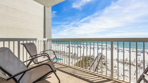 Un balcone con vista su una spiaggia, una piscina e una scala che conduce alla spiaggia.