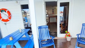 A covered outdoor area with a blue picnic table, two blue chairs, and a life ring mounted on the wall. - Åkrehamn Marina (Karmoy)