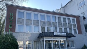 Un hotel con un cartel grande que dice "HOTEL" y un cartel más pequeño que anuncia "Pittahalle", mostrando una lista de servicios.