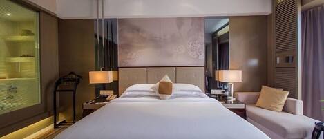 Una habitación de hotel moderna con una cama grande, lámparas de noche, un escritorio y un sofá.