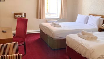 Habitación de hotel con dos camas, un escritorio, una silla y una ventana con cortinas.