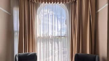 A hotel room with two armchairs, a small round table, and a large window with curtains.
