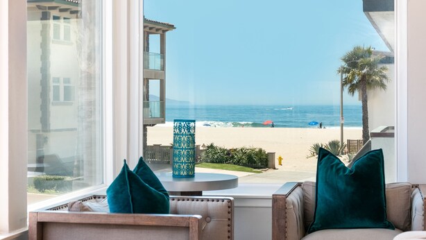 A room with a view of a beach, a round table with a decorative vase, and two chairs with teal cushions. - 5227S -185027: 3  BR, 2  BA House in Oxnard, Sleeps 7 (Oxnard)