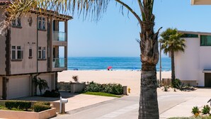 A beachfront property with a two-story building, a palm tree, and a view of the ocean. - 5227S -185027: 3  BR, 2  BA House in Oxnard, Sleeps 7 (Oxnard)