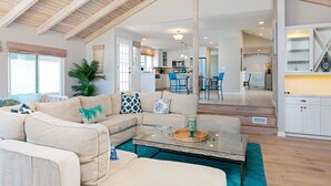 A spacious living room with a high ceiling, a sectional sofa, a coffee table, and a view into the kitchen. - 5227S -185027: 3  BR, 2  BA House in Oxnard, Sleeps 7 (Oxnard)