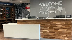 A hotel reception desk with a 'Welcome to the Lone Star State' sign, a 'Hilton Honors' logo, and a 'Spring has sprung' chalkboard.