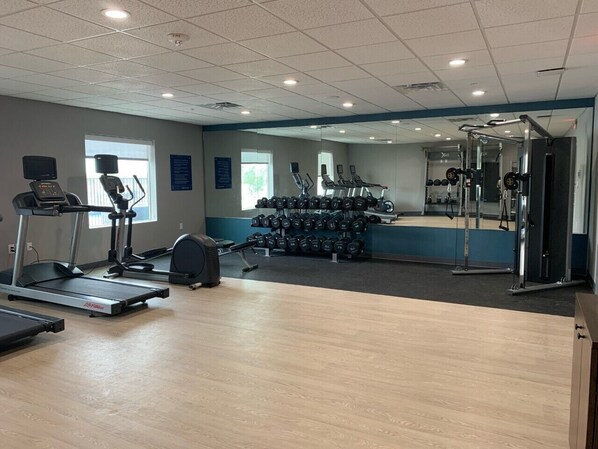 A gym with treadmills, elliptical machines, and free weights.