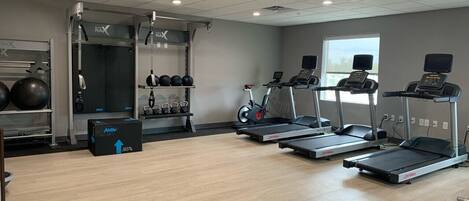 A gym with treadmills, a stationary bike, and a weightlifting area.
