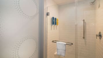 Une douche entièrementClose avec des parois en verre, un porte-serviettes blanc et une porte de douche en verre.