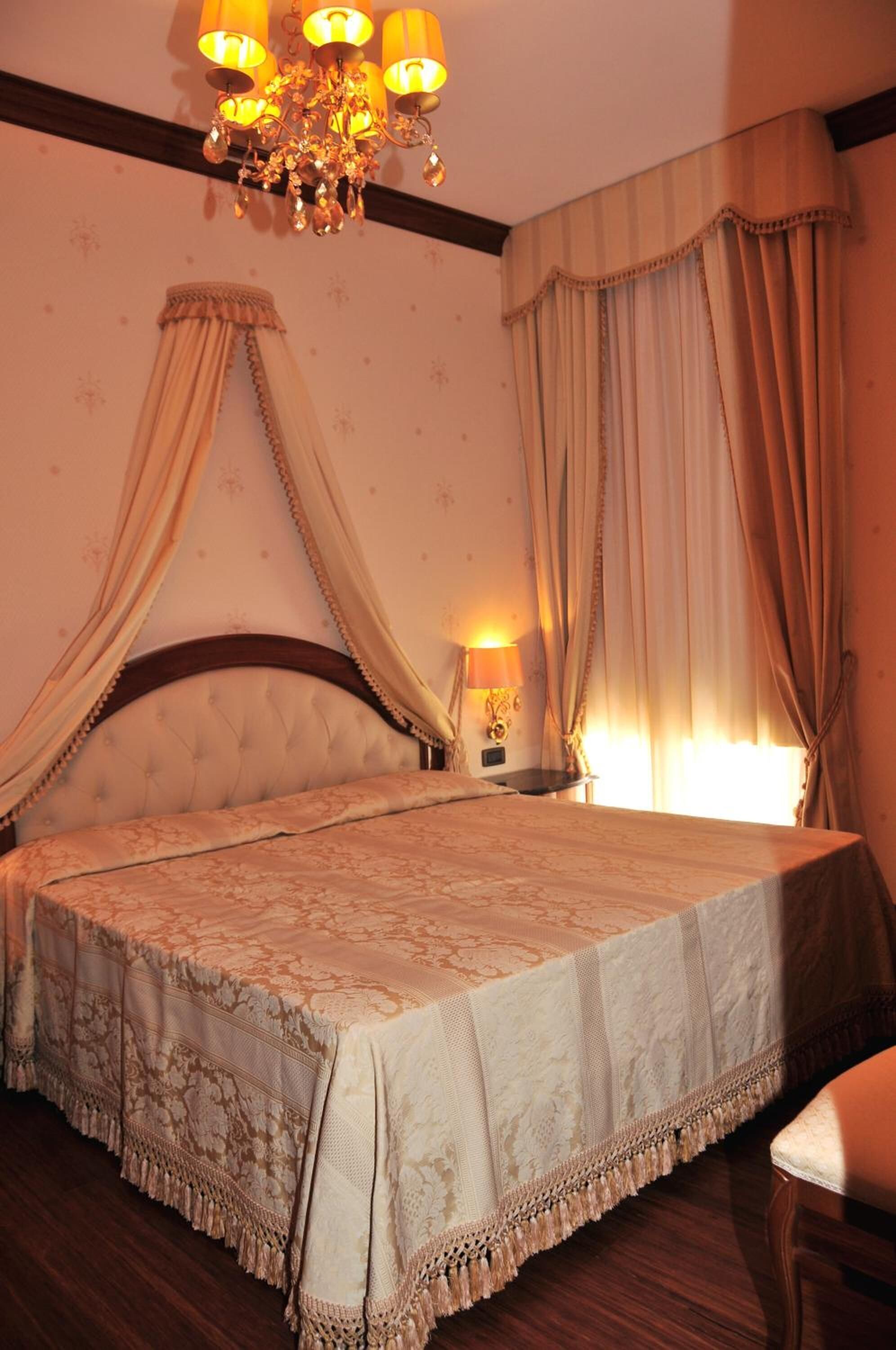 Une chambre à coucher avec un lit à baldaquin, un lustre et des rideaux.