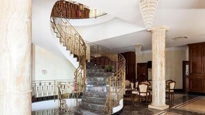 A grand spiral staircase with marble steps and golden railings, leading to an upper floor. - Borgo Don Chisciotte (Modica)
