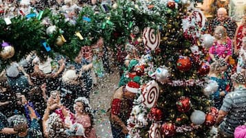 Un espacio interior concurrido, con un gran árbol de Navidad decorado y adornos festivos.