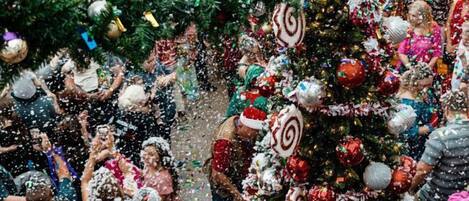 A crowded indoor space with a large decorated Christmas tree and festive decorations.