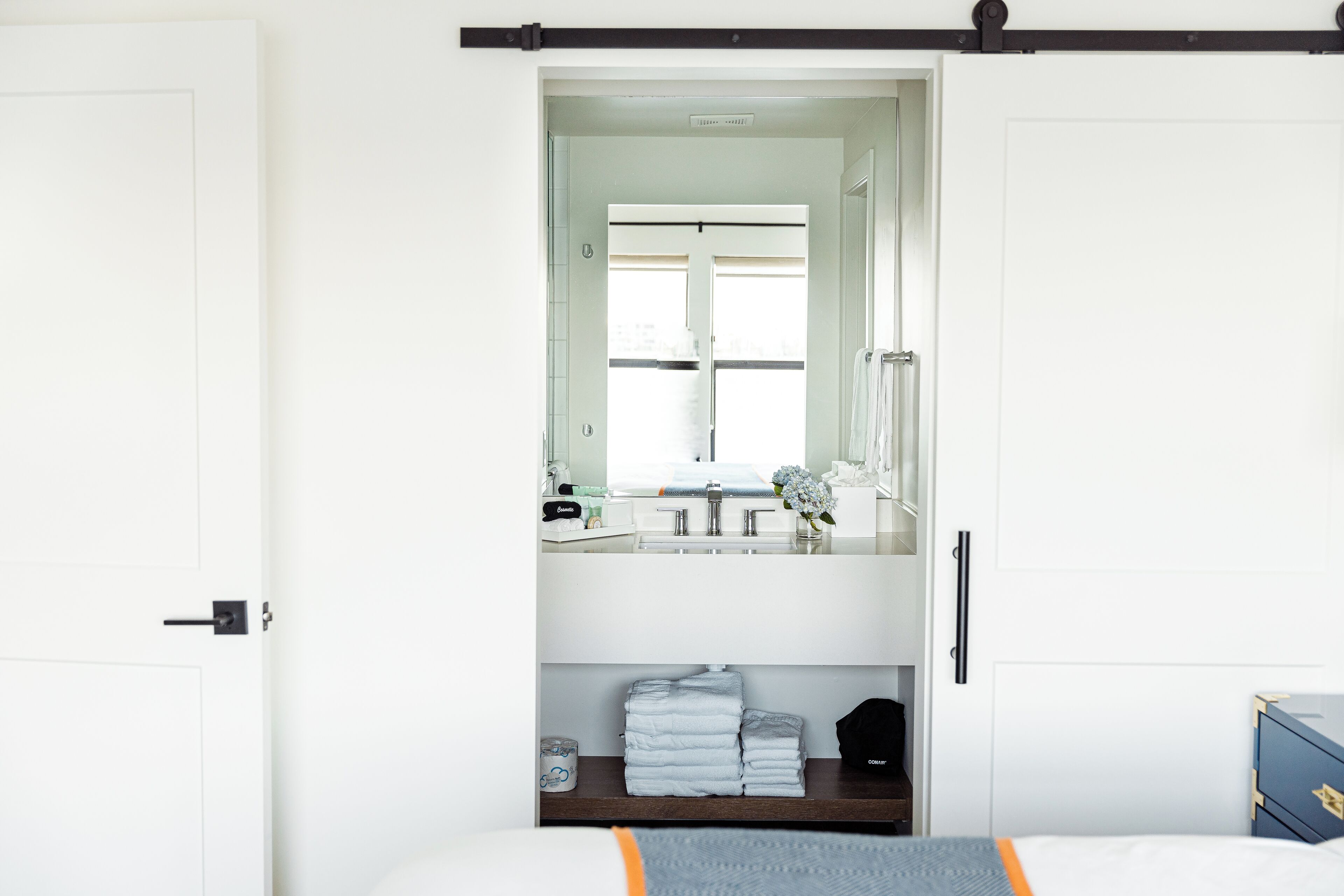 A hotel room with a bed, a bedside table, a mirror, and a window.