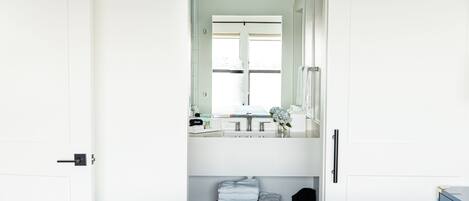 A hotel room with a bed, a bedside table, a mirror, and a window.