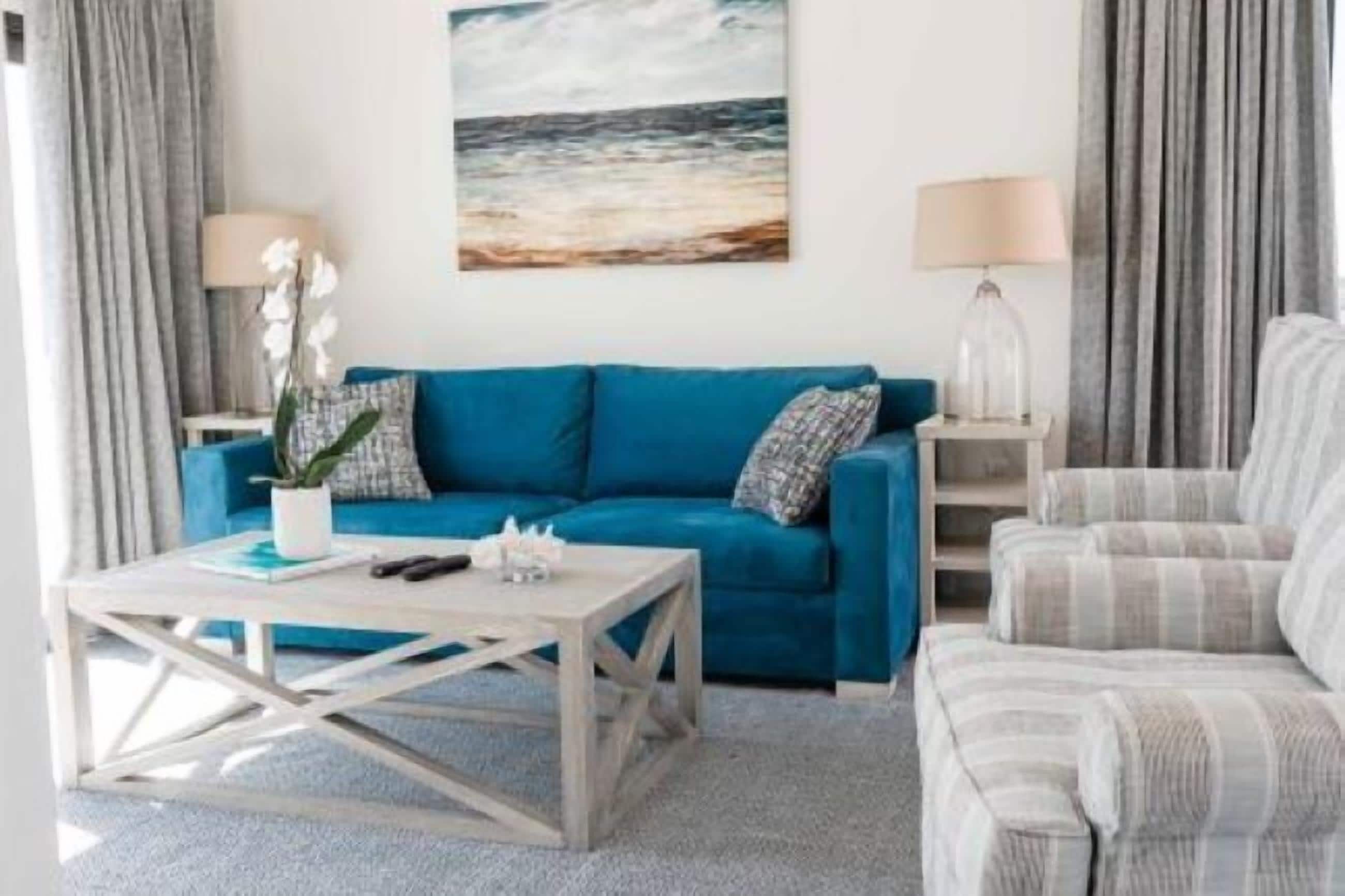 Un soggiorno con un divano blu, una poltrona a righe, un tavolino in legno e una lampada.