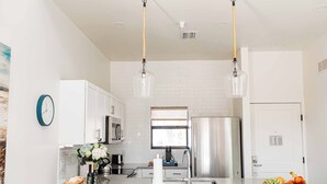A modern kitchen with white cabinets, stainless steel appliances, and pendant lighting. - The Suites at Fishermen’s Village (Punta Gorda)