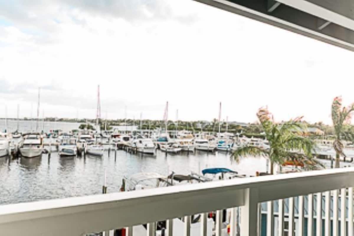 A marina with numerous boats docked, a clear sky, and a view of the water.