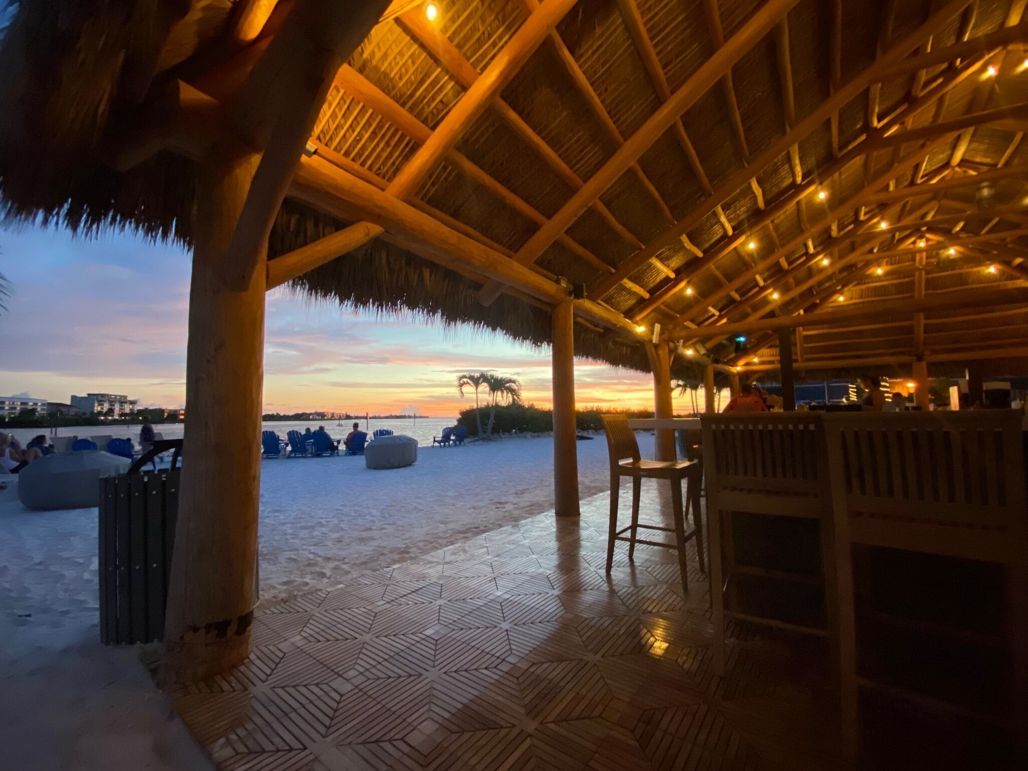 Ein Restaurant direkt am Strand, mit einem Reetdach, Holzboden und Terrassenbestuhlung.