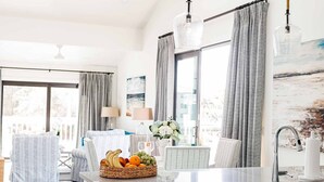 A modern kitchen with a central island, stainless steel appliances, and a dining area with a table and chairs. - The Suites at Fishermen’s Village (Punta Gorda)